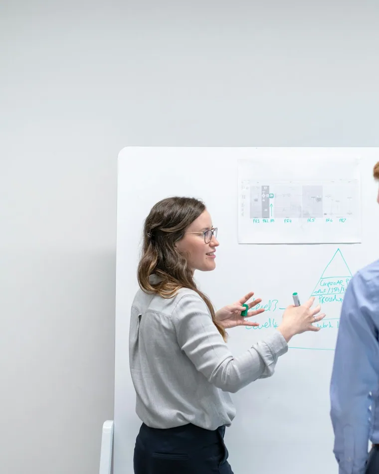 Zwei Fachleute besprechen einen Ablauf am Whiteboard